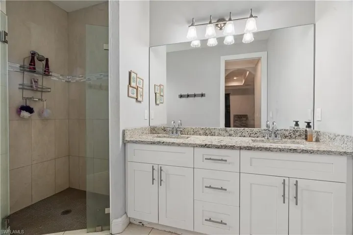 Bathroom featuring tile patterned floors, tiled shower, and vanity