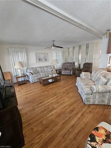Living area featuring a ceiling fan, plenty of natural light, wood finished floors.
