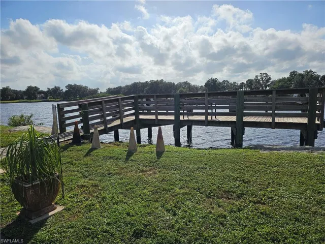 View of dock with a yard and a water view