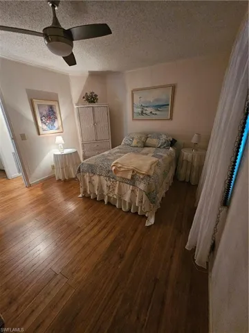 Bedroom with ceiling fan, wood-type flooring, and a textured ceiling