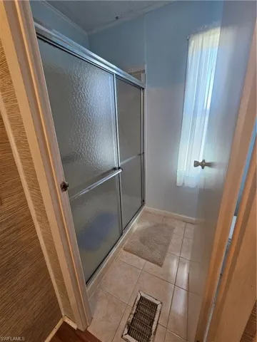 Bathroom with tile patterned floors, visible vents, a textured ceiling, and a shower stall
