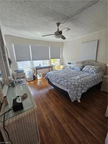 Bedroom with a textured ceiling, a ceiling fan, and hardwood / wood-style flooring