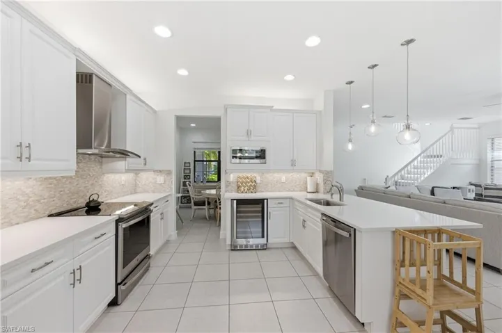 Modern kitchen featuring white cabinetry, stainless steel appliances, a white tile backsplash, a built-in wine cooler, and recessed lighting
