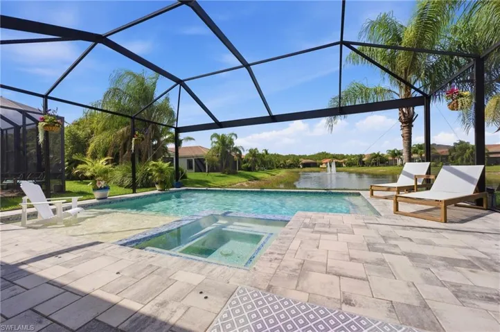 Screened-in outdoor living space featuring a swimming pool, integrated spa, and extensive paver patio