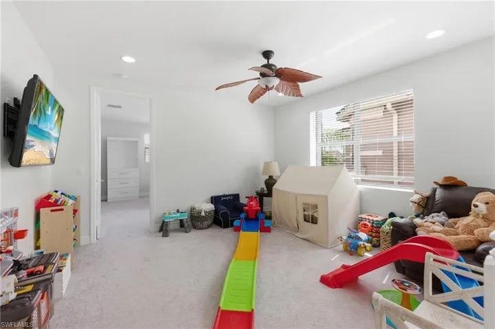 Spacious room featuring light-colored carpet flooring, recessed lighting, and a ceiling fan with leaf-shaped blades