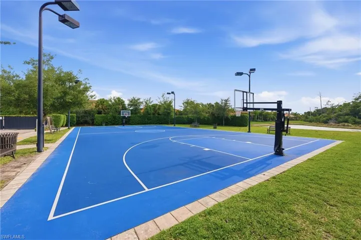 Full-size basketball court featuring a blue playing surface with white line markings, multiple hoops, and integrated overhead lighting