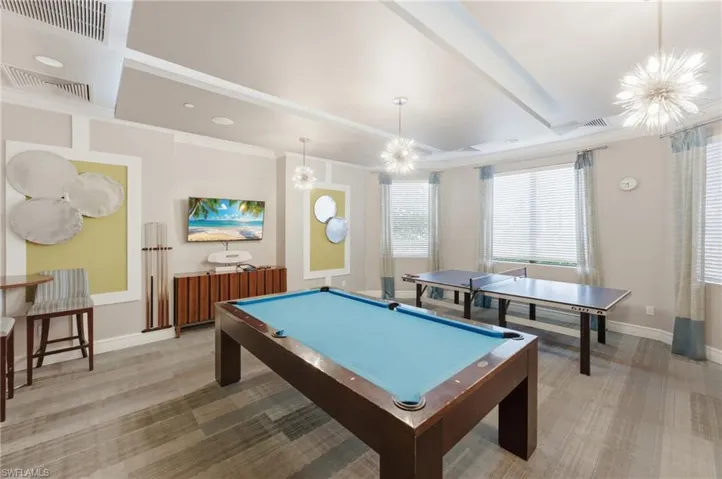 Spacious recreation room featuring wood-finish flooring, recessed lighting, and tray ceilings