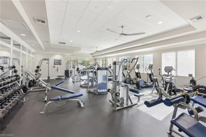 Fitness center featuring a wide array of exercise equipment, rubber flooring, and ample natural light from multiple windows