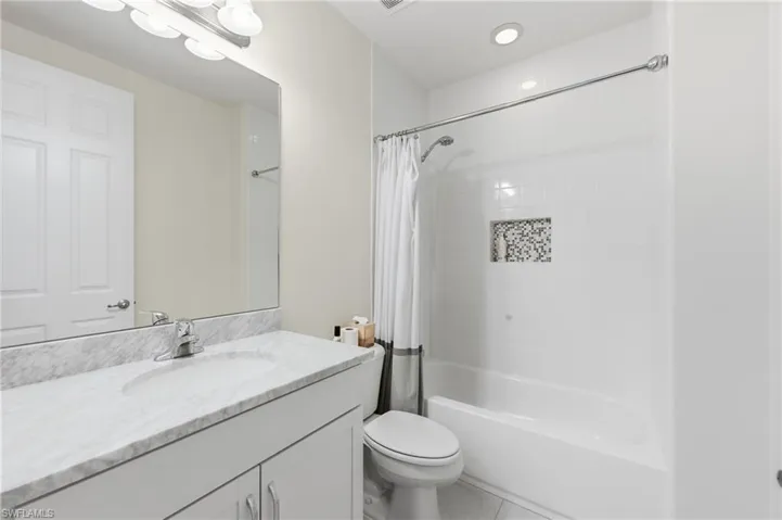 Bathroom featuring a white vanity with a light-toned stone countertop, an undermount sink, and a large wall-mounted mirror