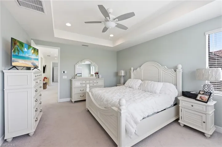 Carpeted bedroom featuring a tray ceiling, recessed lighting, and a ceiling fan