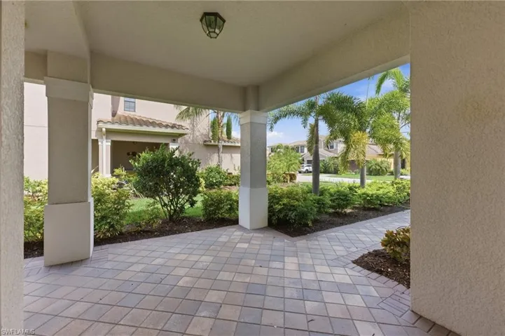 Covered patio featuring paver flooring, stucco columns, and an overhead light fixture