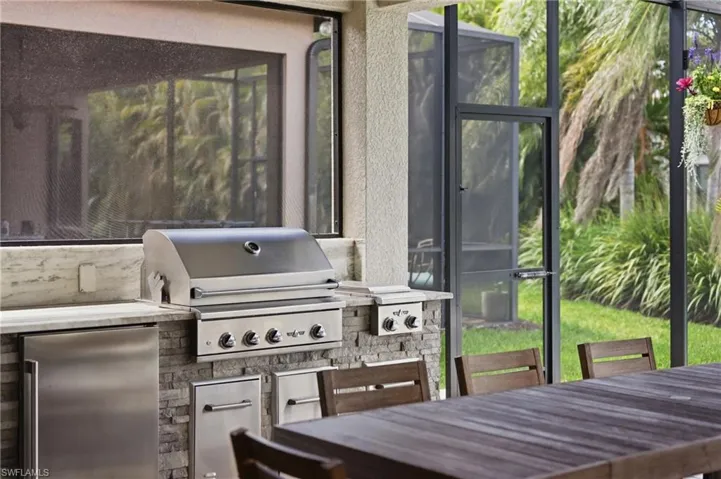 Outdoor kitchen featuring a built-in stainless steel grill, stone veneer base, and light-toned countertop