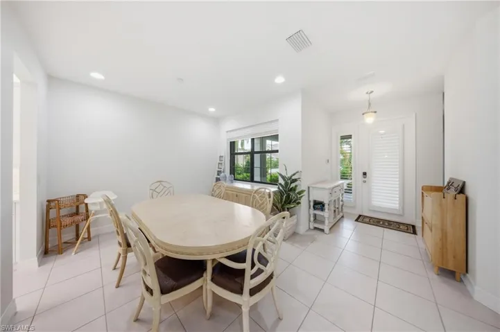 Spacious dining area featuring neutral tile flooring, recessed lighting, and a window with plantation shutters
