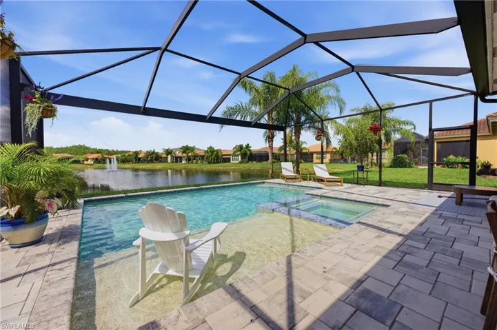 Screened outdoor living area featuring a rectangular pool with an integrated spa, an in-pool sun shelf, and paver decking