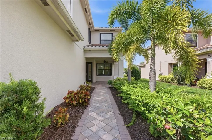 Paver walkway leading to a covered entry with a glass-paneled door
