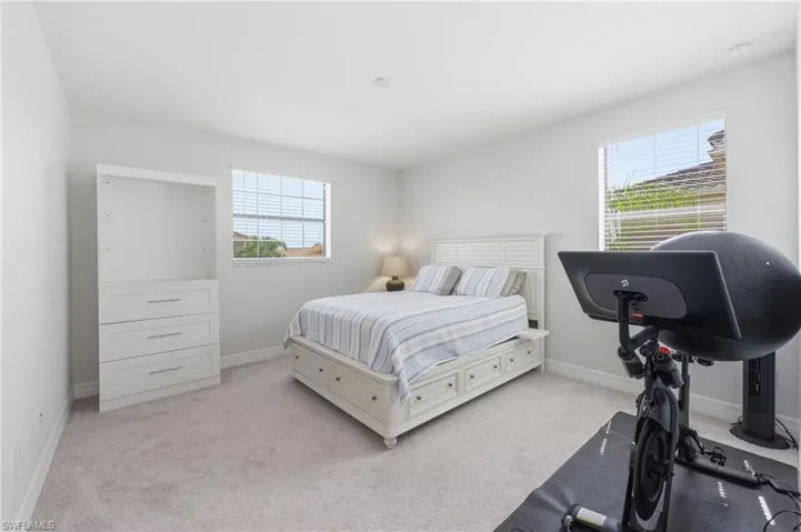 Bright room featuring neutral-toned walls, two windows with horizontal blinds, and light-colored carpeting