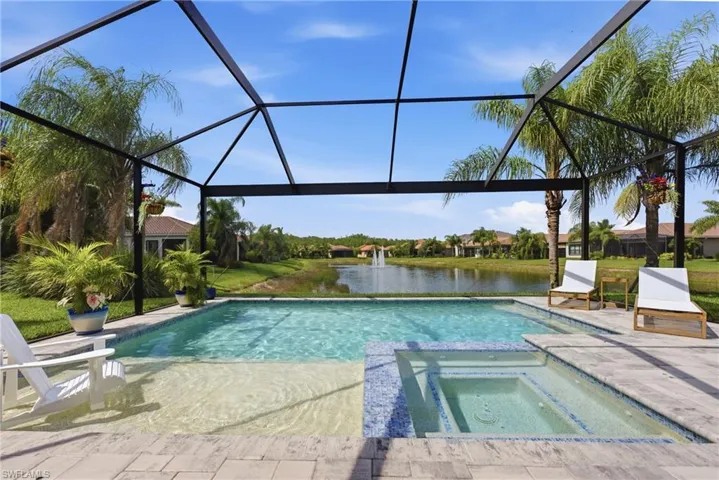 Screened lanai featuring a swimming pool with an integrated spa, sun shelf, and paver decking