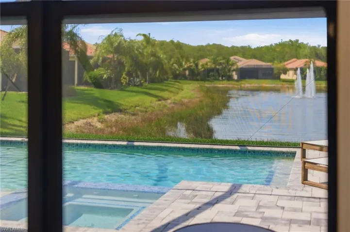 Expansive outdoor area featuring a swimming pool with an integrated spa, paver patio, and screened enclosure