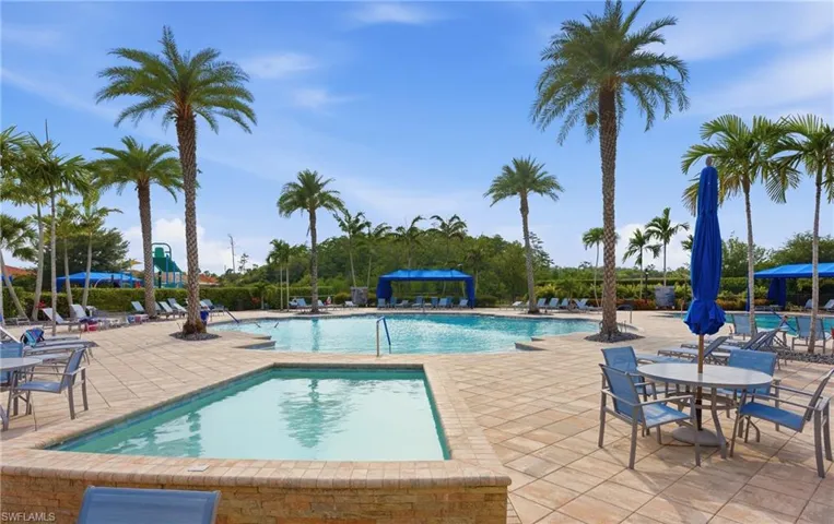 Resort-style pool area featuring a large swimming pool, separate spa, and expansive paver deck