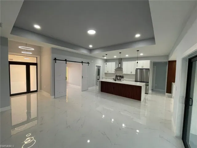Kitchen with a barn door, open floor plan, decorative light fixtures, a raised ceiling, and recessed lighting
