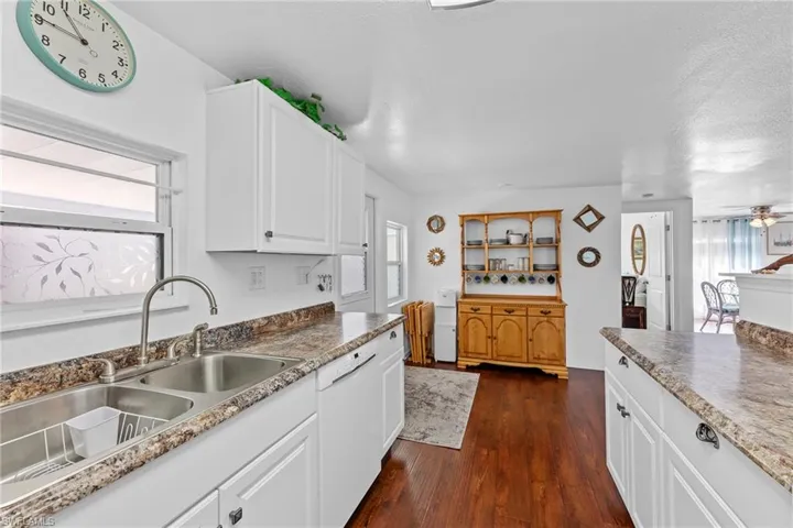 Kitchen featuring white cabinetry, a healthy amount of sunlight, dark hardwood / wood-style flooring, and dishwasher