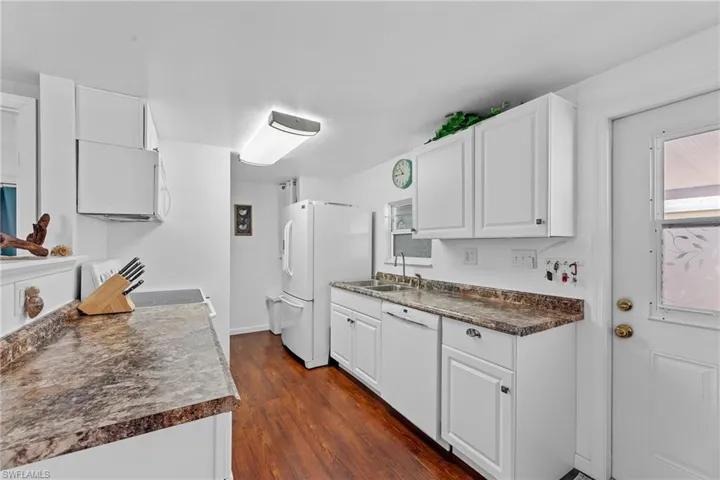 Kitchen featuring dark wood-type flooring, white cabinetry, sink, and white appliances