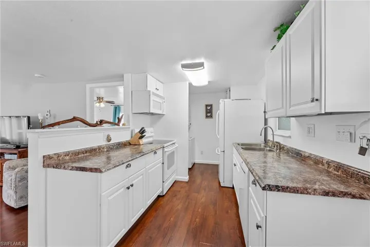Kitchen featuring white cabinetry, white appliances, ceiling fan, dark hardwood floors