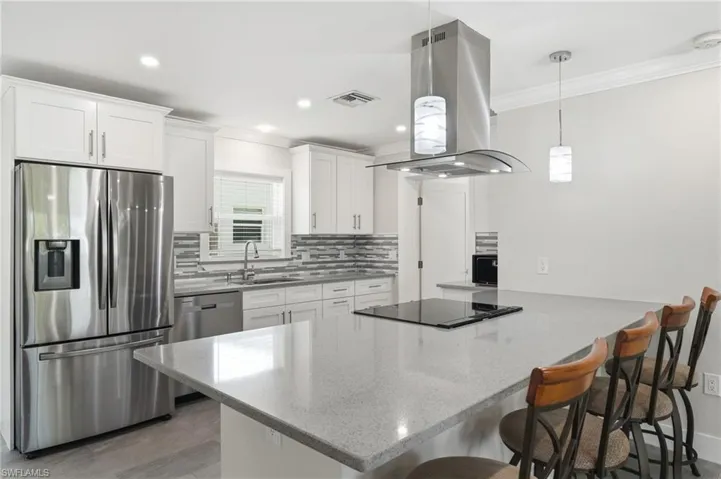 Modern kitchen featuring white shaker cabinetry, stainless steel appliances, and an expansive island with a built-in Glass top range and hood.