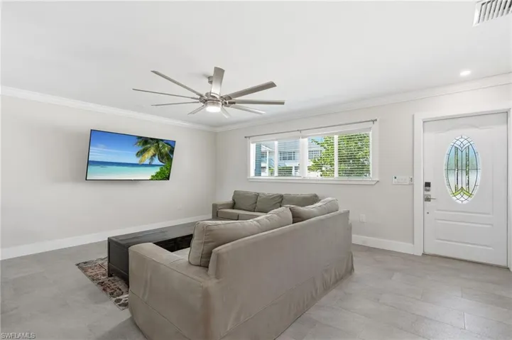 Living area featuring light gray wall paint, crown molding, and wood-finish tile flooring