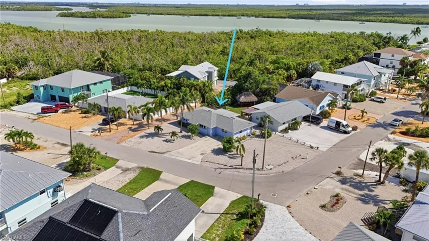 Waterfront property featuring a tropical landscape, mature palm trees, and a gravel yard.