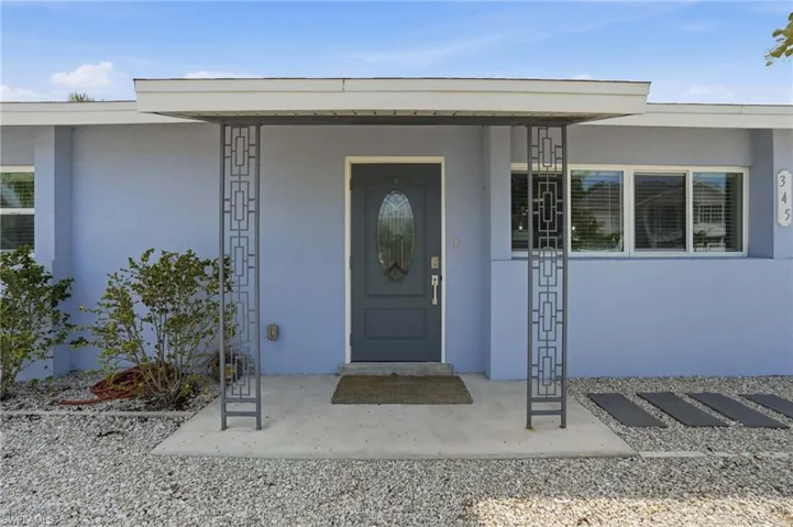 Front entry featuring a covered porch with decorative metal columns, a dark gray oval-lite door.