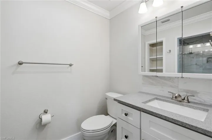 Bathroom vanity featuring a light-colored countertop, undermount sink, and shaker-style cabinetry with dark hardware