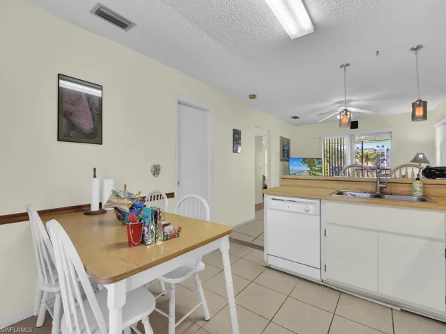 21600 Kitchen with dishwasher, sink, light tile patterned floors, a textured ceiling, and white cabinets