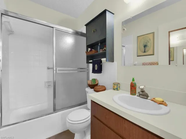 21600 Full bathroom with a textured ceiling, shower / bath combination with glass door, vanity, and toilet