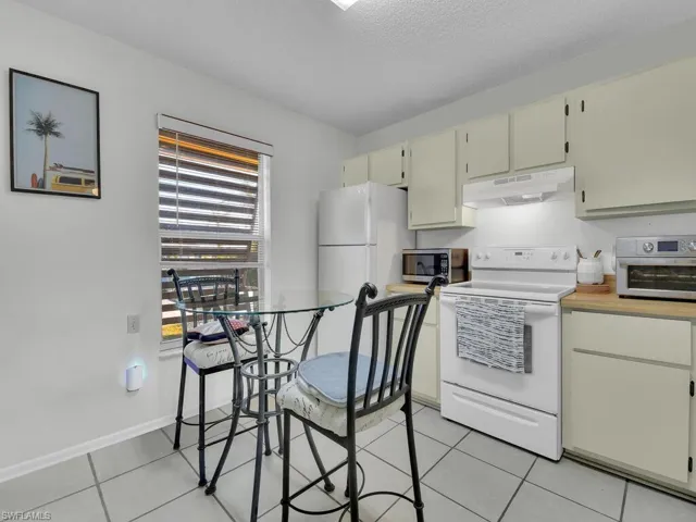 21602 Kitchen with a textured ceiling, light tile patterned flooring, cream cabinets, and white appliances