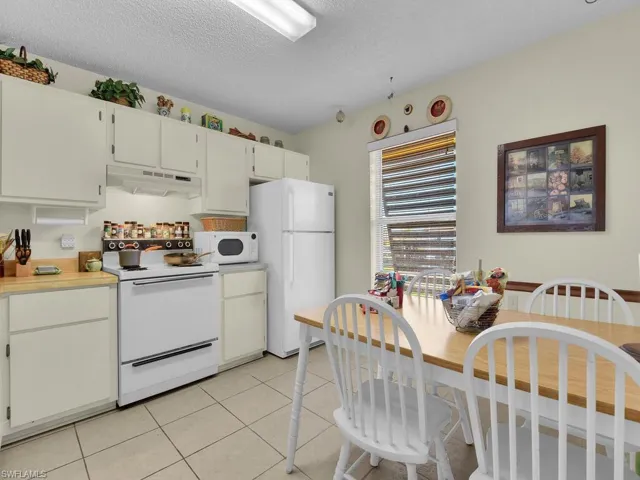 21600 Kitchen featuring a textured ceiling, light tile patterned floors, white cabinetry, and white appliances
