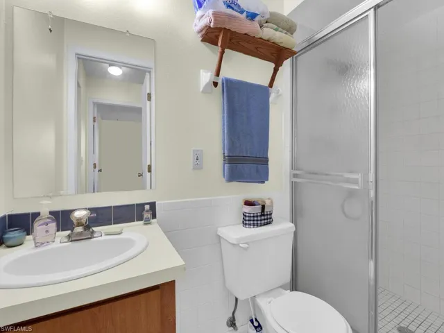 21600 Bathroom with a shower with door, tile walls, toilet, and vanity