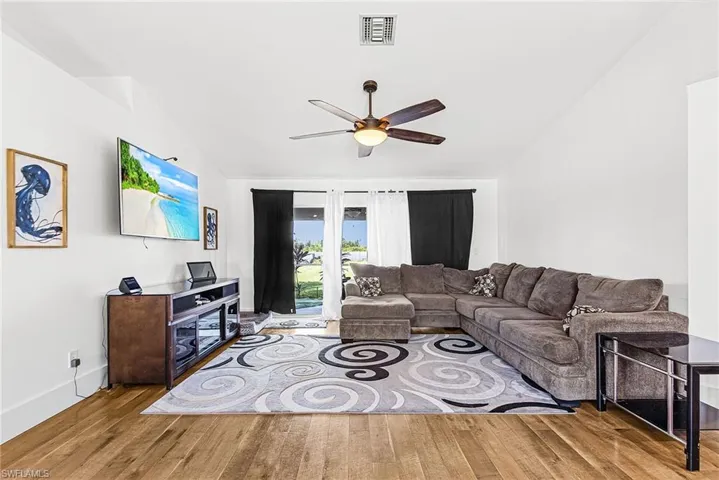 Living room featuring lofted ceiling, light wood-style floors, and ceiling fan