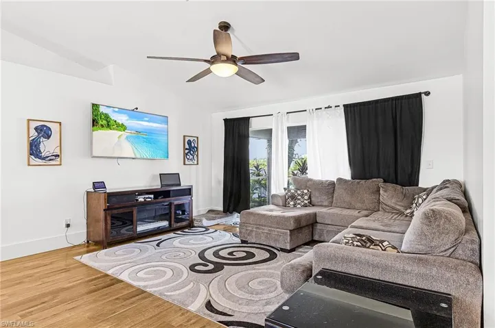 Living room featuring light wood-style floors, a ceiling fan, and lofted ceiling