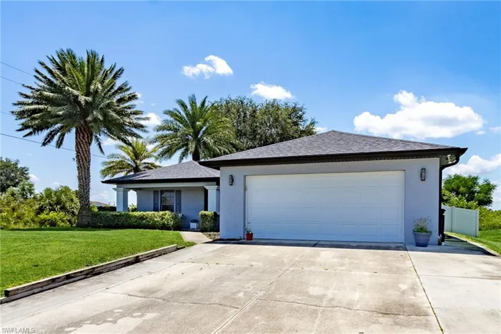 Ranch-style home with stucco siding, concrete driveway, a front lawn, a garage, and roof with shingles