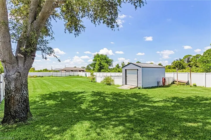 Fenced backyard featuring a storage shed