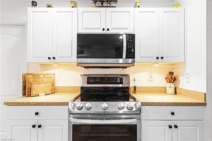 Kitchen with appliances with stainless steel finishes, white cabinetry, and light countertops