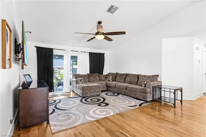 Living room with lofted ceiling, light wood-type flooring, and ceiling fan