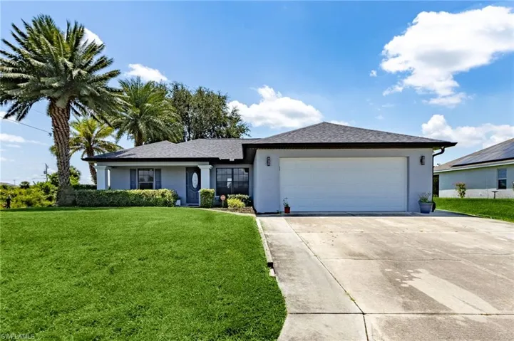 Ranch-style home with stucco siding, a front yard, driveway, and an attached garage
