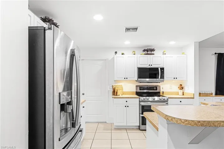 Kitchen with appliances with stainless steel finishes, light countertops, white cabinetry, light tile patterned flooring, and recessed lighting