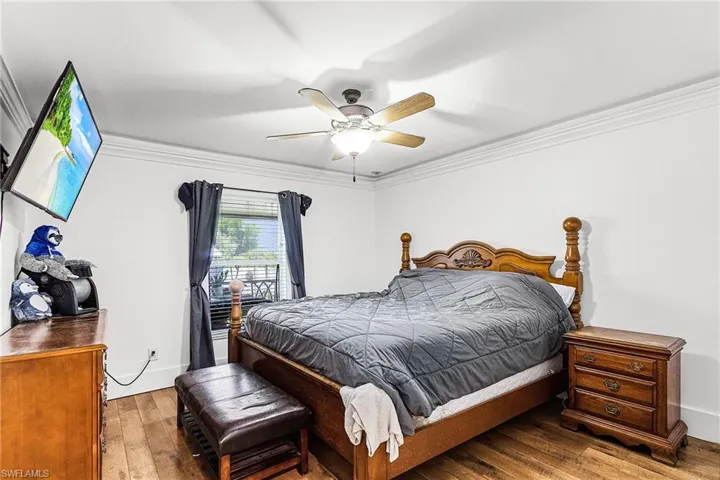 Bedroom featuring ornamental molding, hardwood / wood-style flooring, and ceiling fan