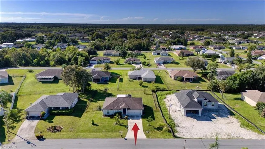 Aerial perspective featuring a single-story residence with a pitched shingle roof, concrete driveway, and attached garage situated on a grass-covered lot