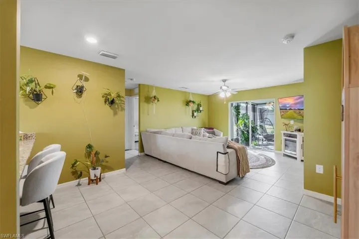 Open-concept interior featuring light-colored ceramic tile flooring, recessed lighting, ceiling fan, and sliding glass doors with exterior access