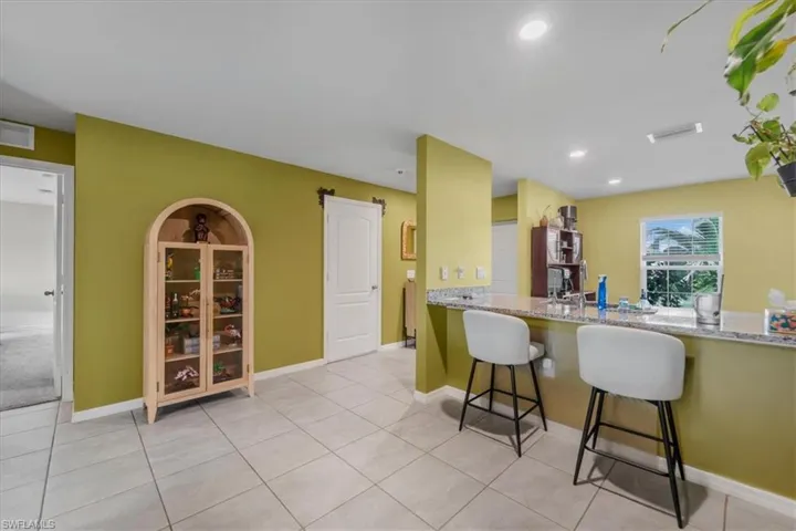 Kitchen area featuring stone-look countertops, a breakfast bar, recessed lighting, and large-format tile flooring