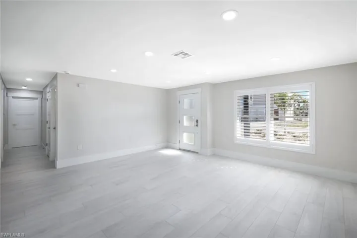 Unfurnished living room with light wood-type flooring, baseboards, visible vents, and recessed lighting